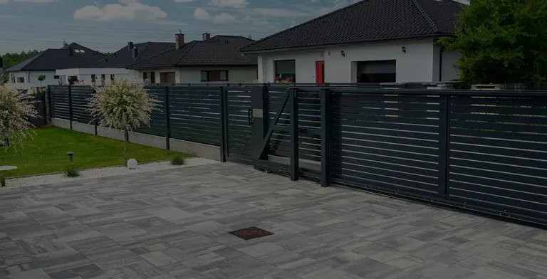 Modern black horizontal slat fence along a residential driveway
